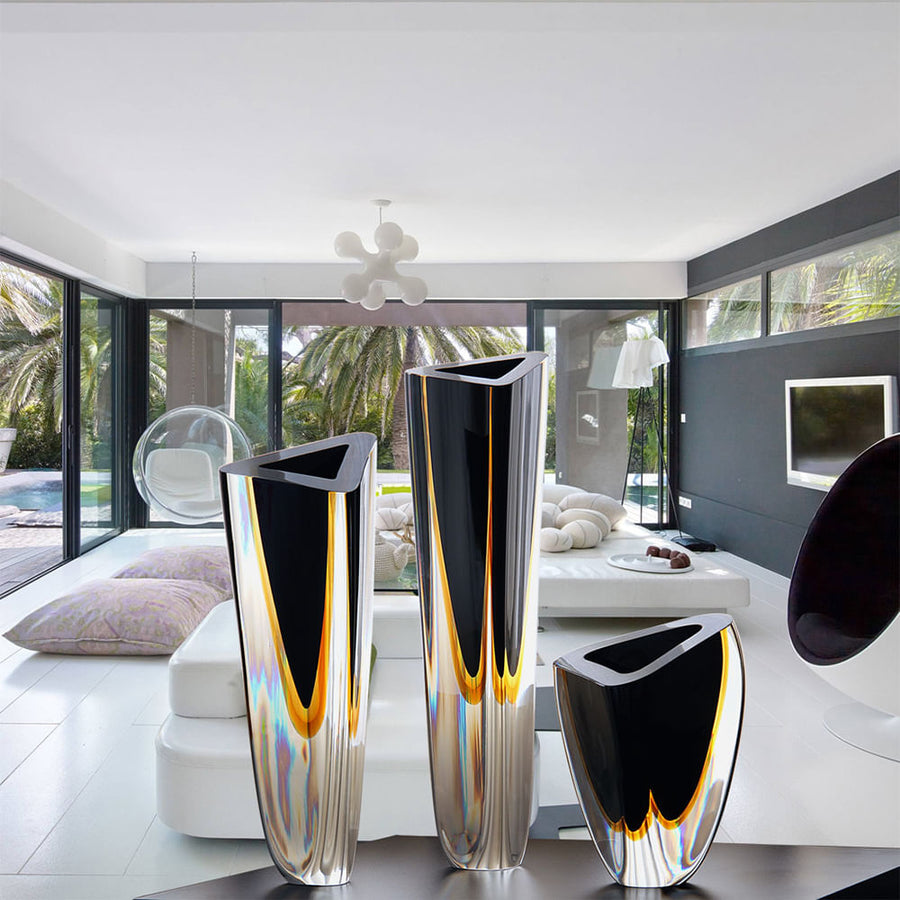 A group of Gardeco Glass Vase Triangle 1 Black Amber vases in a room, displaying contemporary refinement with bicolour glass.