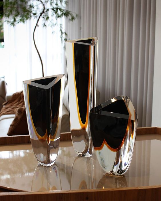 A collection of Gardeco Glass Vase Triangle 1 Black Amber vases displayed on a table.