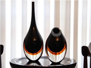 A versatile design of a Gardeco Glass Vase Drop Large Black Amber placed on a sleek black surface.