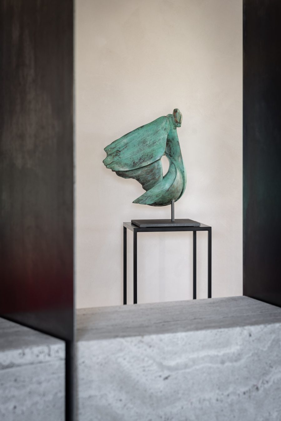 Bronze sculpture on a stand against a neutral wall