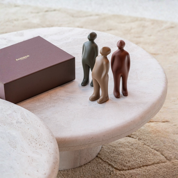 Three small figurines on a marble table next to a giftbox.