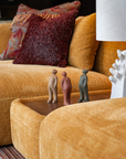 Orange sofa with decorative pillows and a lamp in a living room setting along with ceramic sculptures