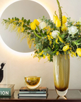 An artistic magnificence of a Gardeco Glass Bowl Flat Diagonal Fume Amber vase of flowers on a table.