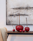 A Gardeco ceramic sculpture of cherry black Ginja mini fruit objects as decor on a wall.