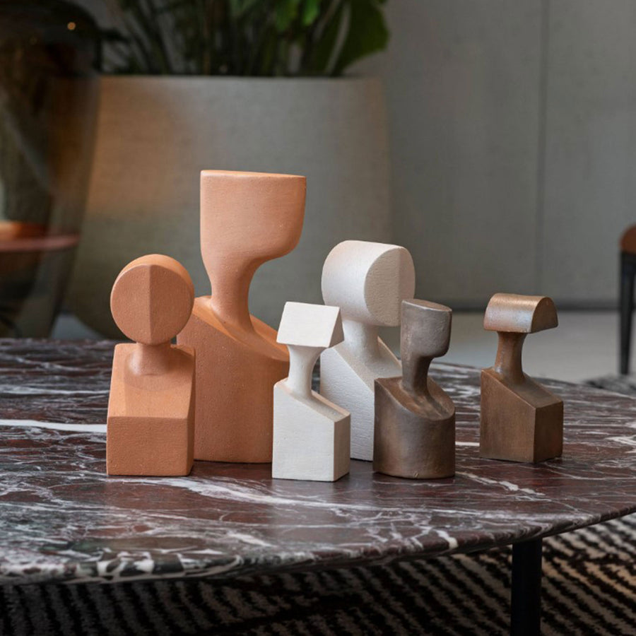 A collection of Gardeco Ceramic Sculpture The Muses Plus Clio Ochre sculptures displayed on a marble table.