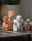 The Gardeco Ceramic Sculpture The Muses Plus Clio White, a group of wooden sculptures on a marble table, showcased in an elegant white finish.
