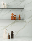 A white marble shelf with Gardeco Ceramic Sculpture The Muses Plus Clio White figurines on it, featuring a beautiful white finish.