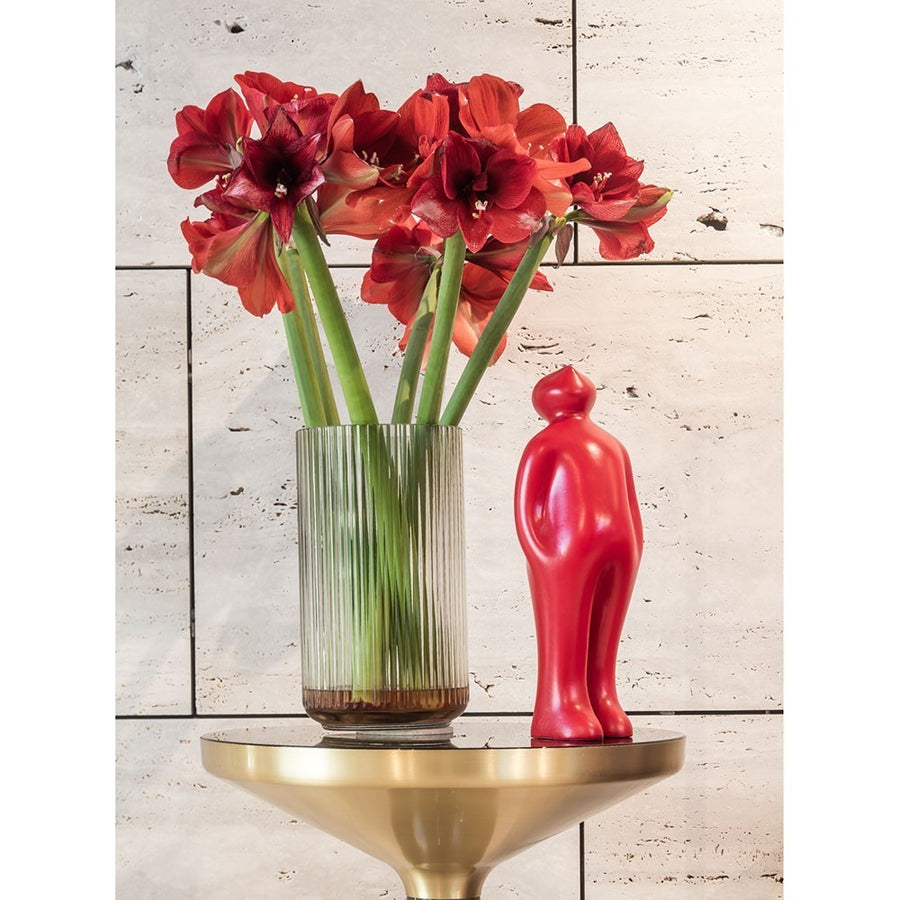 A Gardeco Ceramic Sculpture called "Visitor" featuring red daffodils in a vase on a gold table, showcasing the intersection of art and nature.