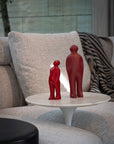 An art sculpture called "Gardeco Ceramic Sculpture Visitor Small Red Urucum" featuring two red figurines on a table.