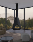 A modern black suspended fireplace with a visible flame, set in a minimalist living room with large floor-to-ceiling windows overlooking a misty forest.
