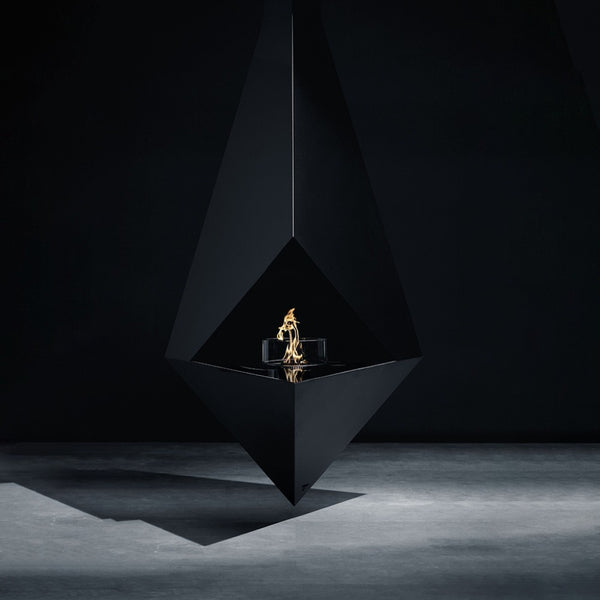 A modern black geometric fire pit with a suspended triangular design, featuring a small gold flame element in the center, set against a dark studio background.