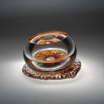 A amber and clear finish glass sculpture from Glasremis on a grey background available at Spacio retail store in Mumbai