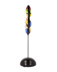 Colorful abstract sculpture on a black stand against a white background