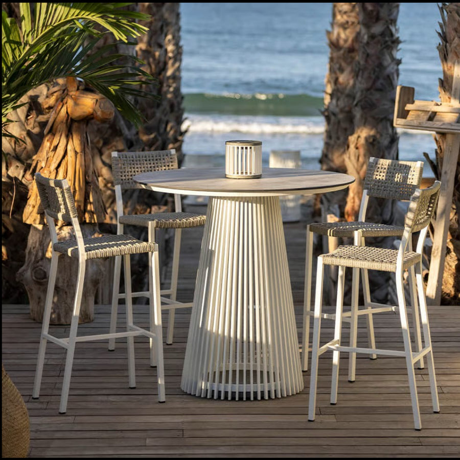 Outdoor patio set with a table and chairs on a wooden deck by the ocean.