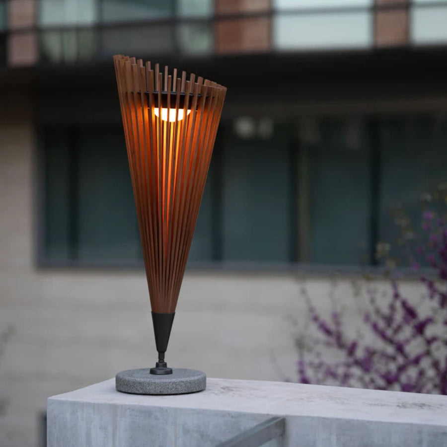Tall, cone-shaped outdoor indoor solar lamp with wooden slats on a concrete surface.