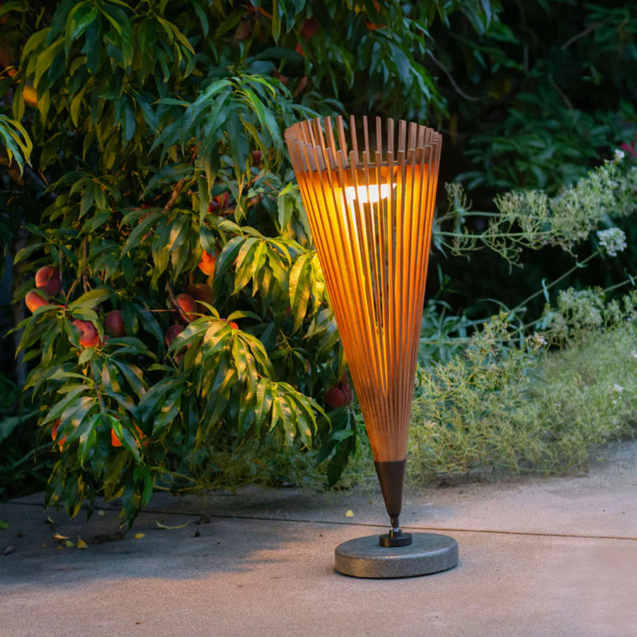 Tall outdoor solar lamp with wooden design on a concrete surface with greenery in the background by Les Jardins available at Spacio retail stores in Mumbai & Kolkata.  