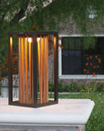 Decorative outdoor solar lantern with wooden slats on a stone ledge in a garden setting  by Les Jardins available at Spacio retail stores in Mumbai & Kolkata. 