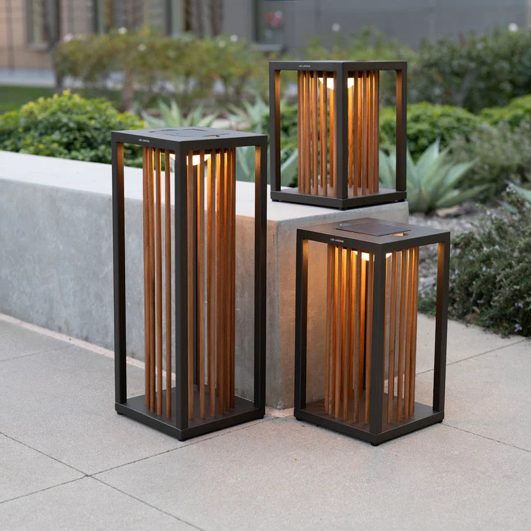 Three outdoor indoor portable and rechargeable solar lanterns with wooden accents on a patio by Les Jardins available at Spacio retail stores in Mumbai & Kolkata. 