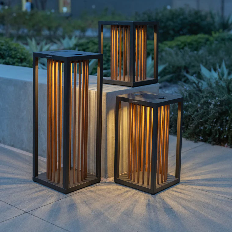 Three outdoor lanterns on a patio with garden in the background  by Les Jardins available at Spacio retail stores in Mumbai & Kolkata. 