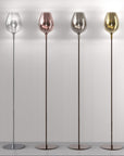 Four floor lamps with different coloured glass shades on a plain background from Italamp available at Spacio in India. 
