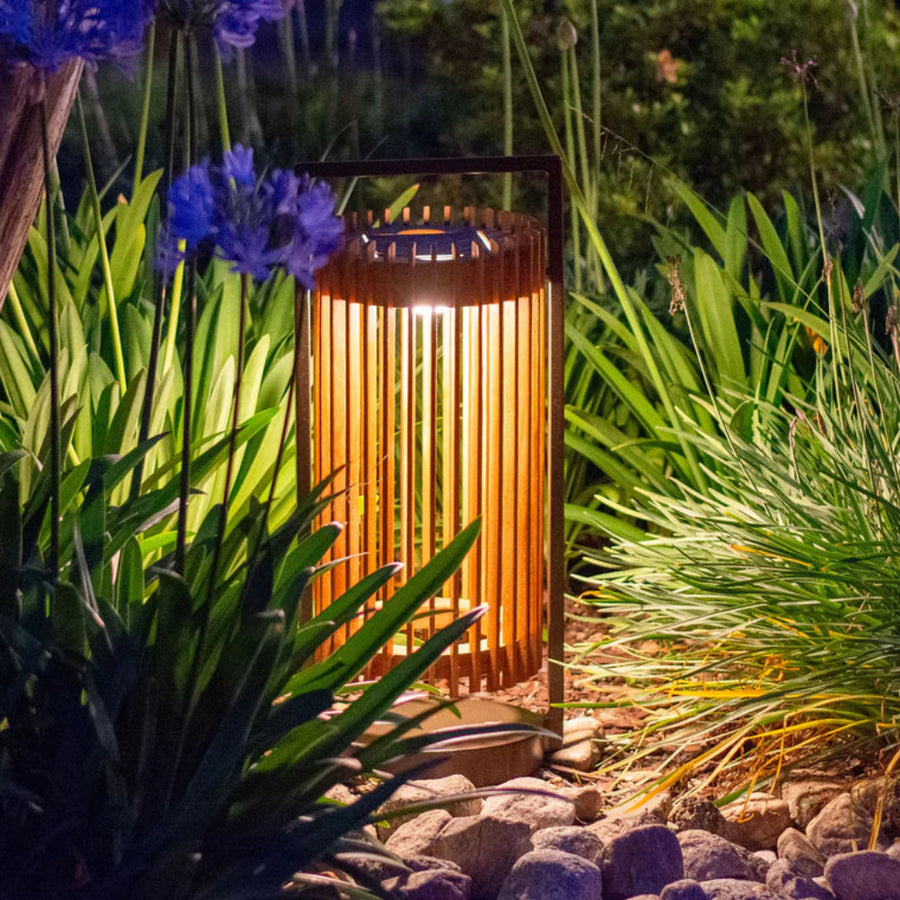 Decorative outdoor solar lantern surrounded by greenery and flowers at night by Les Jardins available at Spacio retail stores in Mumbai & Kolkata.  