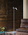 Modern floor lamp next to a brown leather armchair in a room with dark wooden panels.