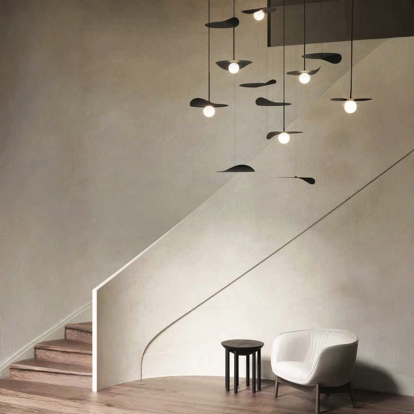 A room with a white chair and a KDLN Flow Ceiling Installation lamp.