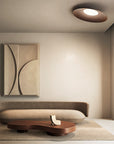 Modern living room with a curved sofa, coffee table, and abstract painting.