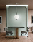 Modern dining area with a small table and chairs against a light green wall.