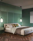 Modern bedroom with green walls, wooden floor, and a bed with decorative pillows.