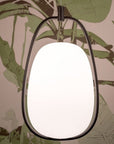 Round mirror with black frame on a leaf-patterned background