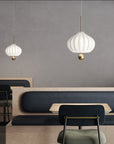 Modern interior with pendant lights, tables, and chairs against a gray wall.