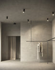 Modern interior with concrete walls and ceiling, featuring a clothes rack with hanging garments.