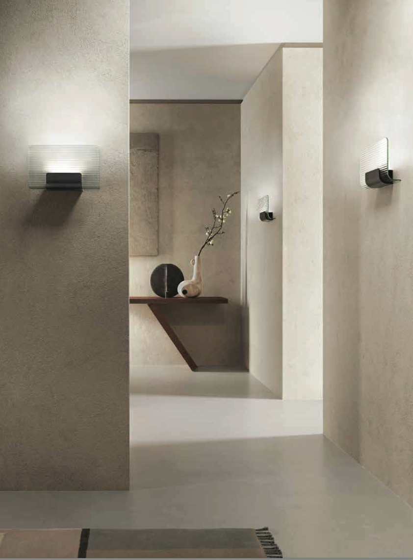 A modern hallway with a KDLN Nami Wall Sconce featuring a varnished aluminium structure and a textured glass diffuser.