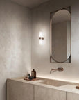 Modern bathroom with a sink, mirror, and wall light fixture.