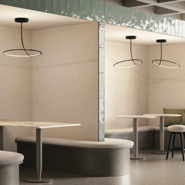 A dining room with adjustable tables and dimmable chairs in the middle of the room, illuminated by a KDLN Poise Ceiling Lamp.
