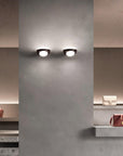 Modern wall lights on a gray wall with shelves displaying bags.