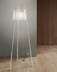 Modern floor lamp with a white base and shade on a wooden floor against a gray wall.