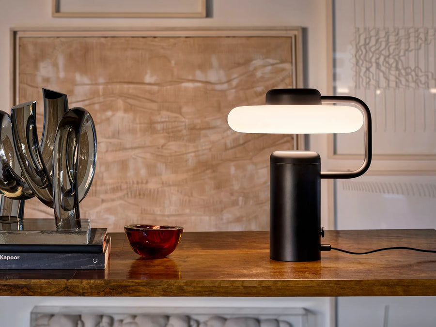 KDLN Tratto Table Lamp in black finish on a wooden console table next to luxury decor accessories. Available at Spacio retail stores in India. 