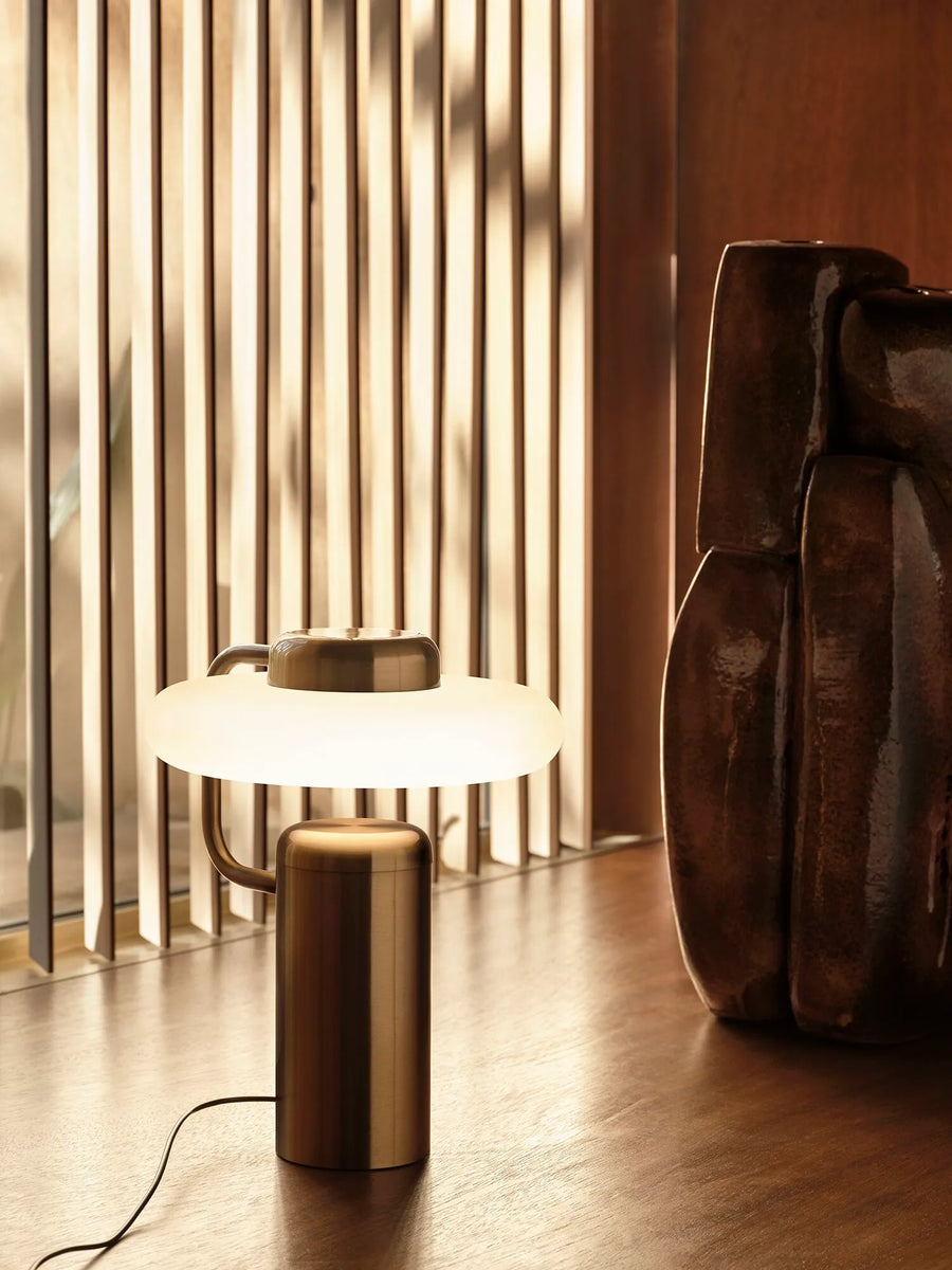 KDLN Tratto Table Lamp in black finish styled on a floor next to a floor sculpture. Available at Spacio retail stores in India. 