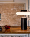 KDLN Tratto Table Lamp in black finish on a wooden console table next to luxury decor accessories. Available at Spacio retail stores in India. 