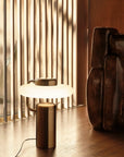 KDLN Tratto Table Lamp in black finish styled on a floor next to a floor sculpture. Available at Spacio retail stores in India. 