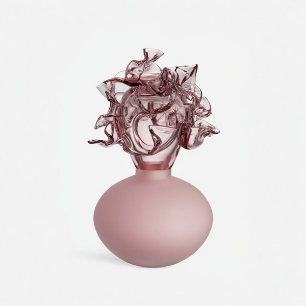 A sculptural object with a matte dusty pink rounded base and a highly textured, ruffled translucent pink glass top, set against a clean light gray background.