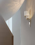Modern wall sconce on a white wall with a staircase in the background