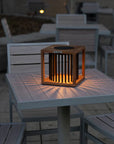 Wooden outdoor table lamp on a table with chairs and tables in the background