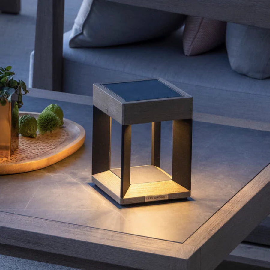 Modern outdoor solar lamp on a wooden table with a blurred background by Les Jardins available at Spacio retail stores in Mumbai & Kolkata.  