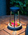 Outdoor solar table lamp with flowers on a wooden table outdoors by Les Jardins available at Spacio retail stores in Mumbai & Kolkata.  