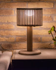 Wooden indoor & Outdoor solar table lamp on a side table against a brick wall