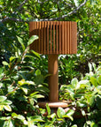 Wooden outdoor solar lamp with slatted design in a natural setting by Les Jardins available at Spacio retail stores in Mumbai & Kolkata.  