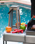 Outdoor grill with vegetables and a solar lantern by a pool